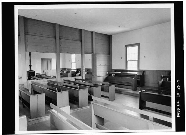 Large room with rows of wooden benches facing inward